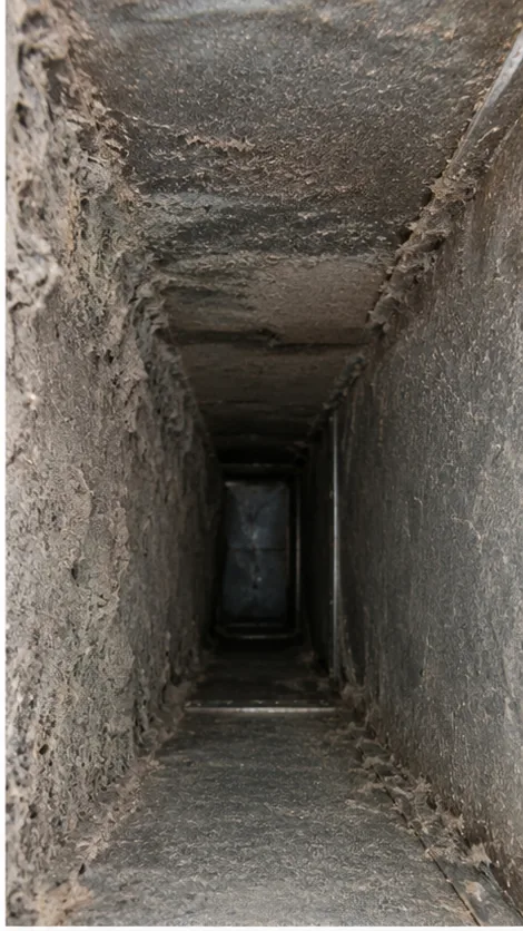 Inside a dirty air duct coated in thick dust and debris before cleaning